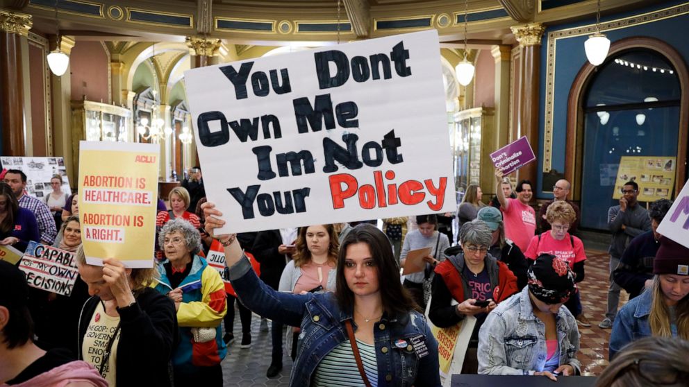 FILE - Marissa Messinger, of Lake View, Iowa, center, holds a sign during a rally to protest recent abortion bans, May 21, 2019, at the Statehouse in Des Moines, Iowa. The Iowa Supreme Court on Friday, June 17, 2022, cleared the way for lawmakers to 