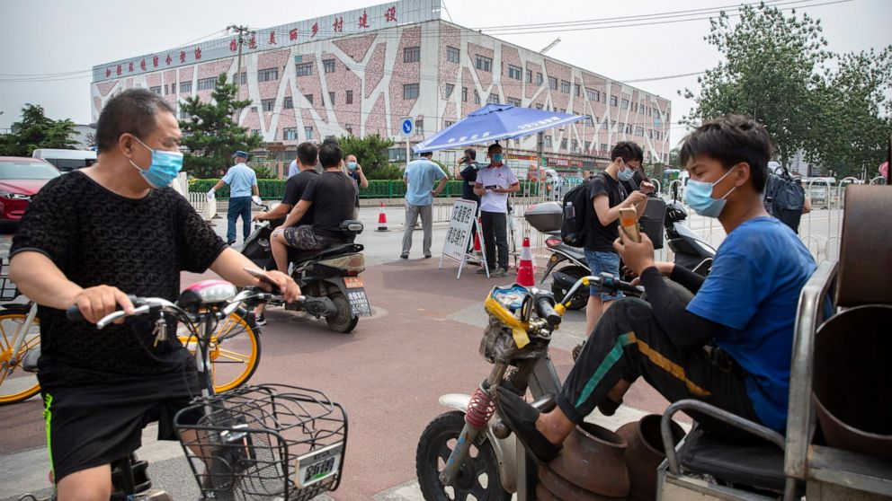 People wearing face masks to protect against the new coronavirus stop at a checkpoint outside the Xinfadi wholesale food market district in Beijing, Saturday, June 13, 2020. Beijing closed the city's largest wholesale food market Saturday after the d