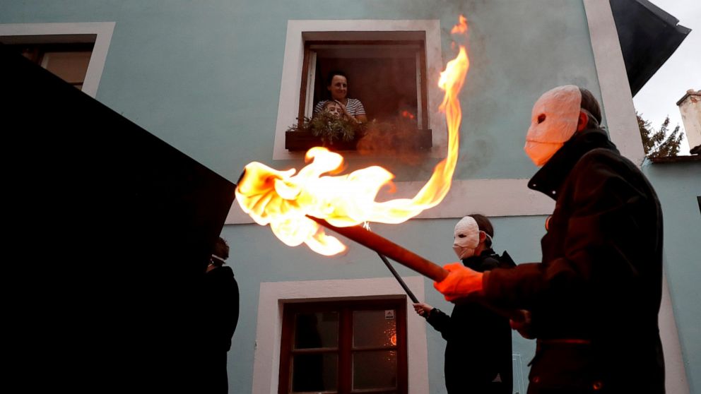 People watch from the window of their home as participants dressed in black, wearing masks, beating drums and pushing small carts making a synchronized and loud sound take part in an Easter procession marching through the streets of Ceske Budejovice,