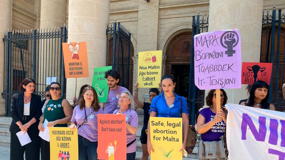 FILE - Activists hold up banners in both English and Maltese reading, 'I decide', 'Abortion is a woman's right', and 'Abortion is healthcare, not a crime', as they stand outside the Maltese law courts in Valletta, Malta, Wednesday, June 15, 2022. Mal