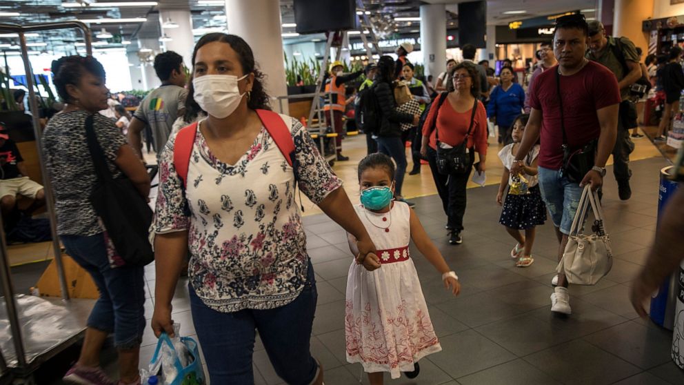 Wearing masks, passenger Gladys Ruiz Torres walks with her daughter Natali Oliva to the departure lounge at the international airport in Lima, Peru, Friday, March 6, 2020. Peruvian President Martin Vizcarra announced the first case of the new coronav