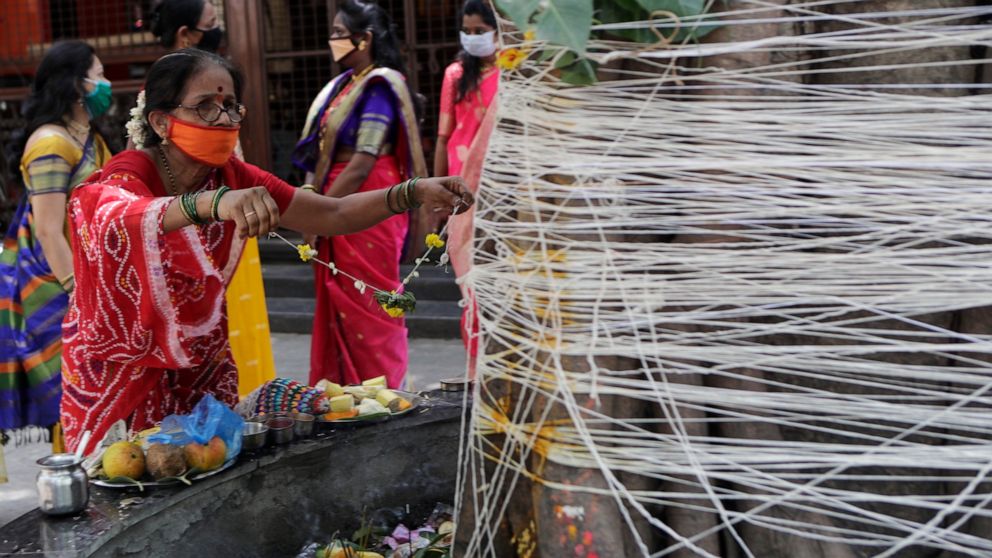 A woman perform rituals with ceremonial thread around a banyan tree on Vat Savitri festival in Mumbai, India, Friday, June 5, 2020. Vat Savitri is celebrated on a full moon day where women pray for the longevity of their husbands. (AP Photo/Rajanish 