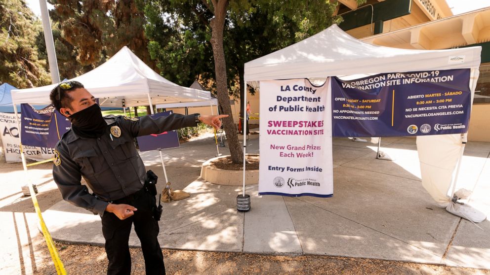 A private security guard gives directions to people looking to get vaccinated, as banners advertise the availability of the Johnson & Johnson and Pfizer COVID-19 vaccines at a county-run vaccination site offering free walk-in with no appointment need