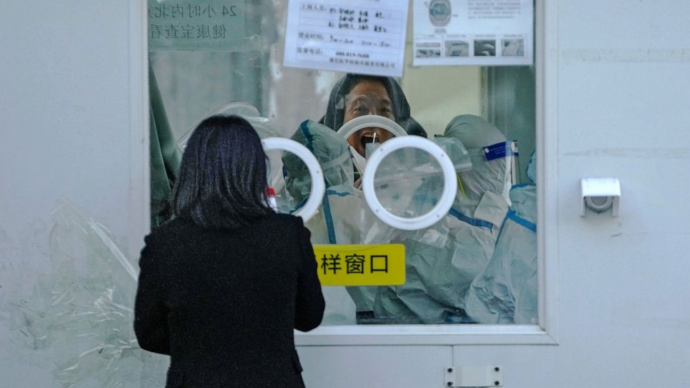 FILE - A man has his routine COVID-19 throat swab at a coronavirus testing site in Beijing, Tuesday, Dec. 6, 2022. China on Wednesday, Dec. 7, 2022, announced new measures rolling back COVID-19 restrictions, including limiting lockdowns and testing r