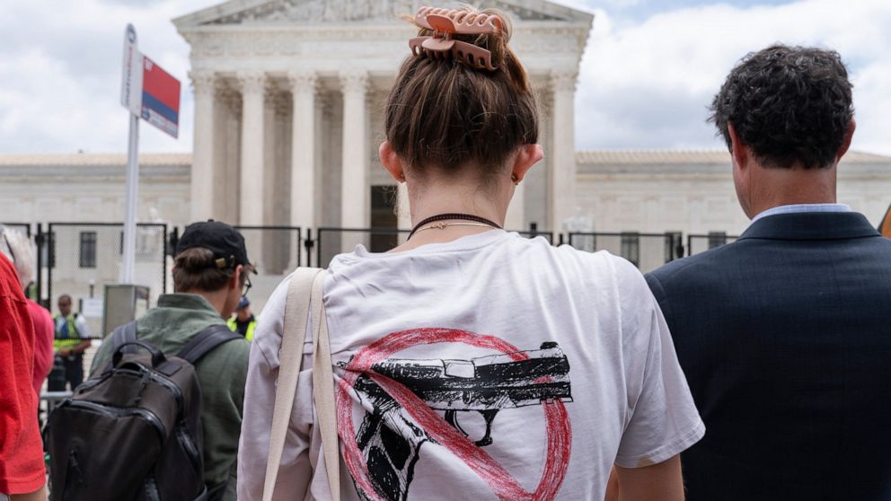A woman wears an anti-gun T-shirt outside of the Supreme Court, following the Supreme Court's decision to overturn Roe v. Wade in Washington, Friday, June 24, 2022. The Supreme Court on Thursday struck down a New York state law that had restricted wh