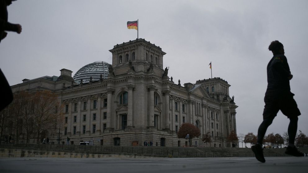 People jogging in front of the Reichstag building with the German parliament Bundestag in Berlin, Germany, Wednesday, Nov. 17, 2021. In its session on Thursday Nov. 18, 2021, the Bundestag wants to vote on new measures to battle the fourth wave of th