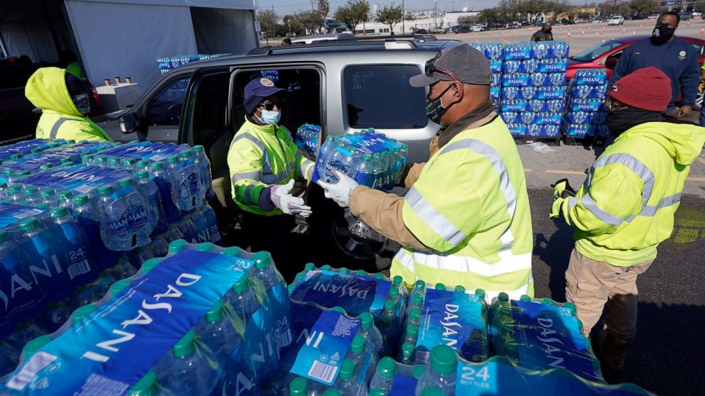 Water is loaded into a vehicle at a City of Houston water distribution site Friday, Feb. 19, 2021, in Houston. The drive-thru stadium location was setup to provide bottled water to individuals who need water while the city remains on a boil water not