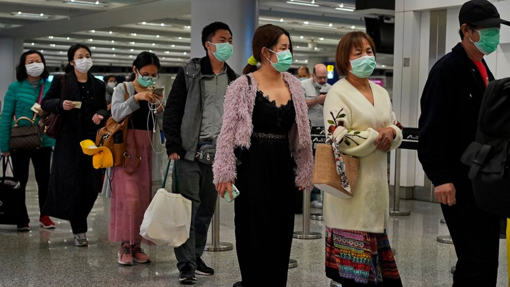 Passengers wear masks as they walk at the Hong Kong International Airport in Hong Kong Saturday, Jan. 25, 2020. Hong Kong has declared the outbreak of a new virus an emergency and will close primary and secondary schools for two more weeks after the 