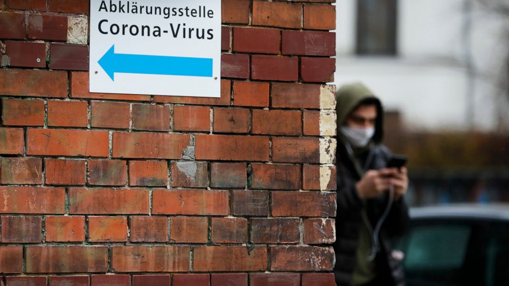 A man with a mask pass an information sign directing to a new set up test and information centre for the new coronavirus at the district Prenzlauer Berg in Berlin, Germany, Monday, March 9, 2020 (AP Photo/Markus Schreiber)