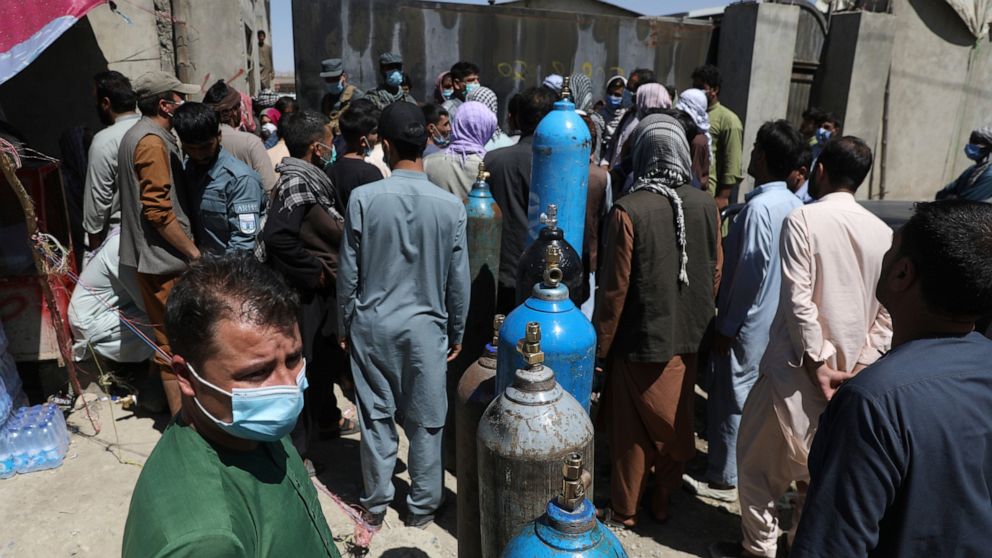 Men wait outside a privately owned oxygen factory to get their oxygen cylinders refilled, in Kabul, Afghanistan, Saturday, June 19, 2021. Health officials say Afghanistan is fast running out of oxygen as a deadly third surge of COVID worsen. (AP Phot