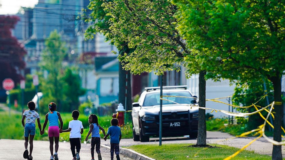 FILE - Children walk hand-in-hand near the scene of a shooting at a supermarket in Buffalo, N.Y., May 15, 2022. The shooting rampage at a Buffalo supermarket, carried out by an 18-year-old who was flagged for making a threatening comment at his high 