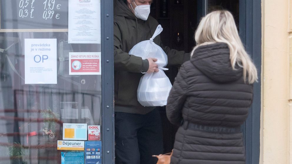 FILE- A man wearing a face mask carries a takeaway lunch from a restaurant in the Old town of Bratislava Slovakia, Nov. 25, 2021. On Monday Jan. 10, 2022, Slovakia has been easing coronavirus restrictions after a decline in new infections while the f