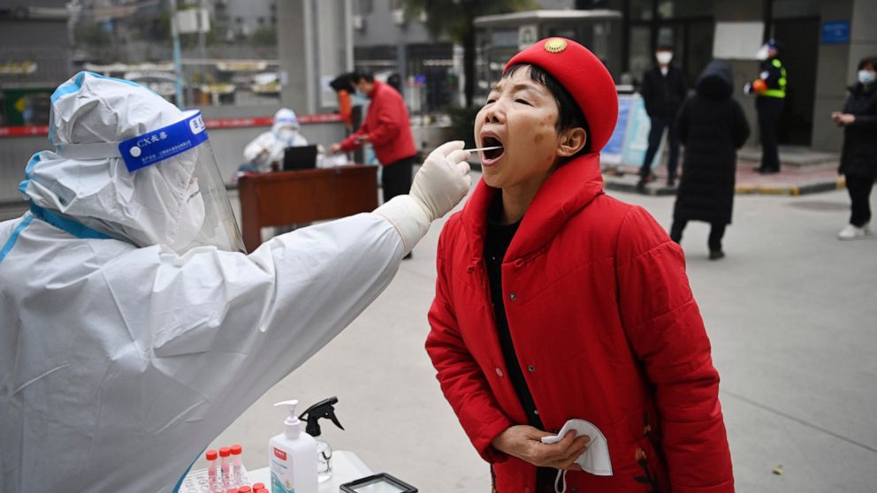 In this photo released by China's Xinhua News Agency, a worker wearing protective gear gives a COVID-19 test to a woman at a testing site in Xi'an in northwestern China's Shaanxi Province, Tuesday, Jan. 4, 2022. China is reporting a major drop in loc