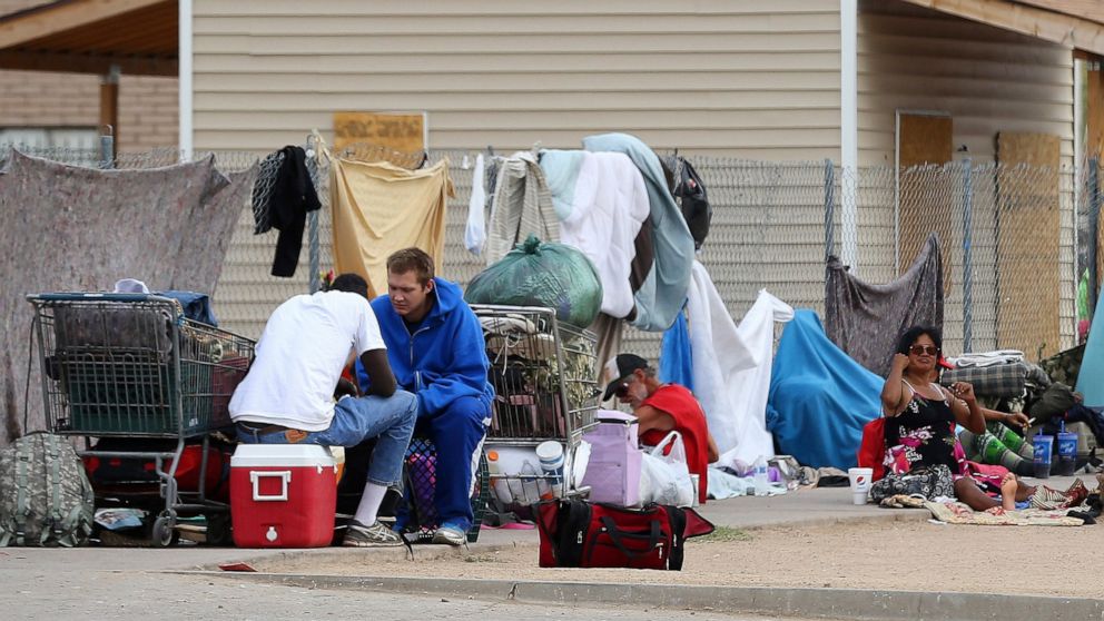 In this May 2, 2019, photo homeless people gather on the sidewalk at an encampment in Phoenix. Health officials say Arizona is seeing a surge in hepatitis A cases, with the majority of people infected being the homeless population and drug users, pri