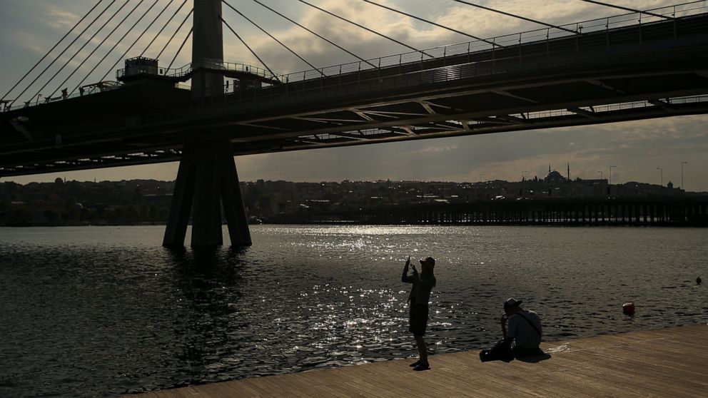 A woman takes a picture by the Golden Horn, leading to the Bosphorus Strait separating Europe and Asia, in Istanbul, Friday, May 14, 2021.Turkey is in the final days of a full coronavirus lockdown and the government has ordered people to stay home an