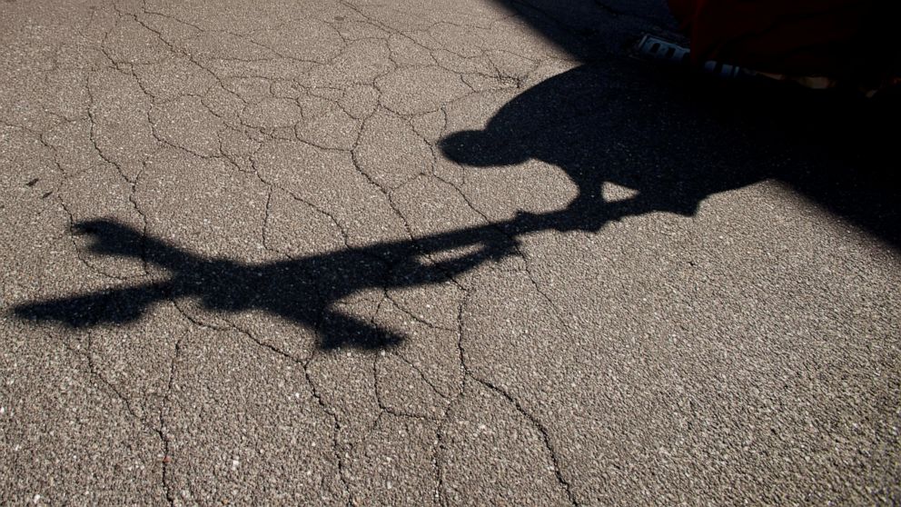 FILE - In this Friday, April 10, 2020. file photo, the shadow of a priest holding a crucifix is cast on the ground as he leads the Via Crucis, or Way of the Cross ceremony, at the Ospedale di Circolo in Varese, Italy. Two authoritative religious bodi