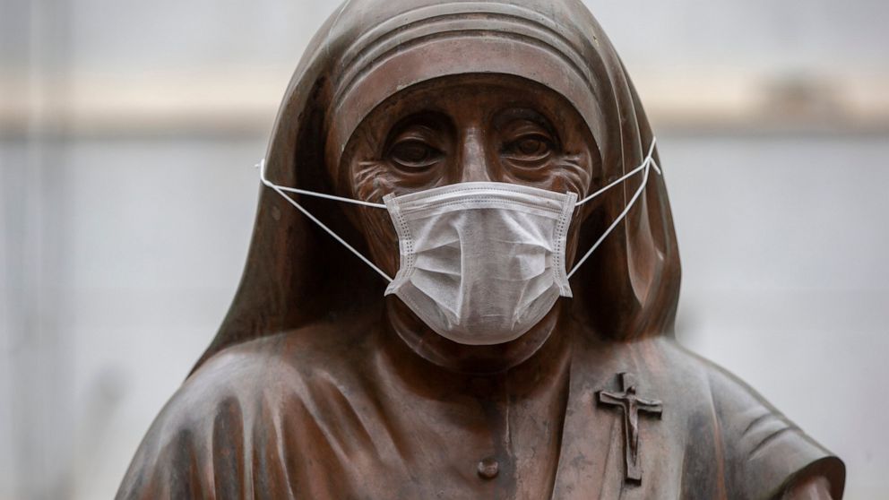 A mask covers the mouth and nose of the St. Mother Theresa with a child statue during smog and heavy air pollution in Kosovo capital Pristina, on Friday, Dec. 20, 2019. (AP Photo/Visar Kryeziu)