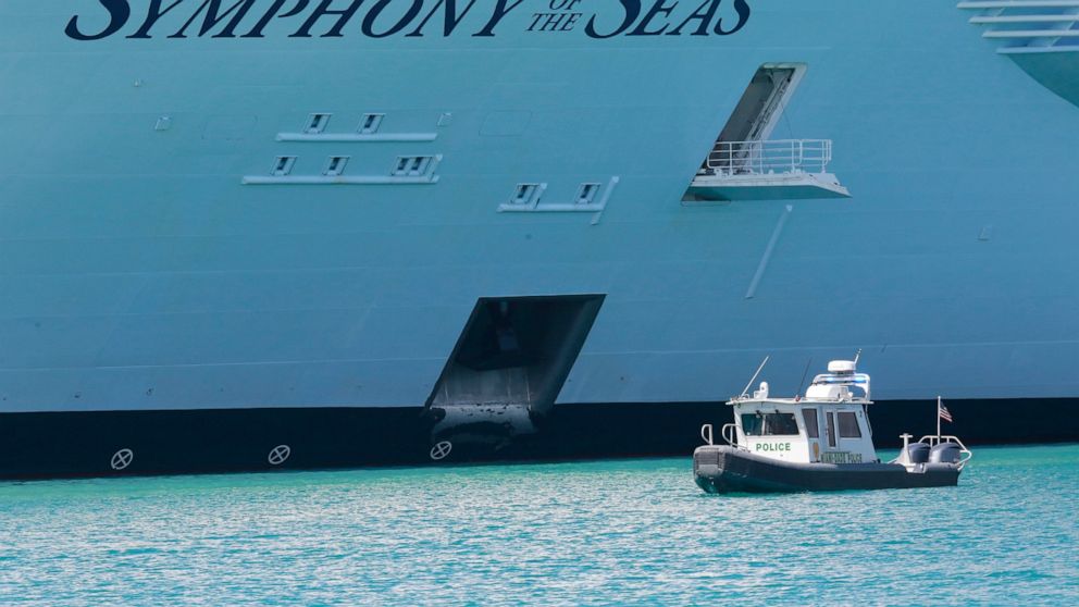 FILE- In this March 14, 2020 photo, police boat guards the Symphony of the Seas cruise ship docked in Miami. The family of Pujiyoko, a cruise crew member who died after testing positive for COVID-19, has filed a lawsuit against Royal Caribbean Cruise