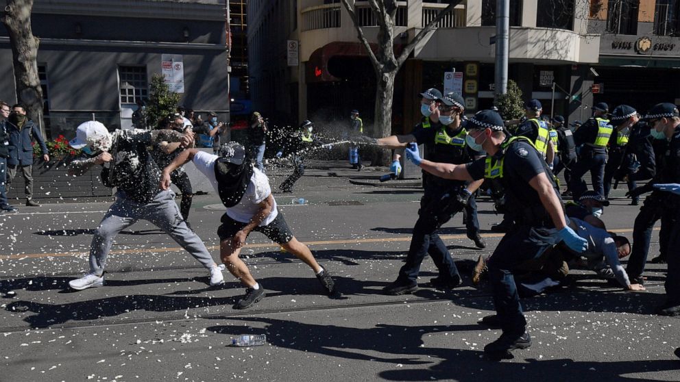 Police use pepper spray on protesters during an anti-lockdown protest in Melbourne, Australia, Saturday, Aug. 21, 2021. Protesters are rallying against government restrictions placed in an effort to reduce the COVID-19 outbreak. (James Ross/AAP Image