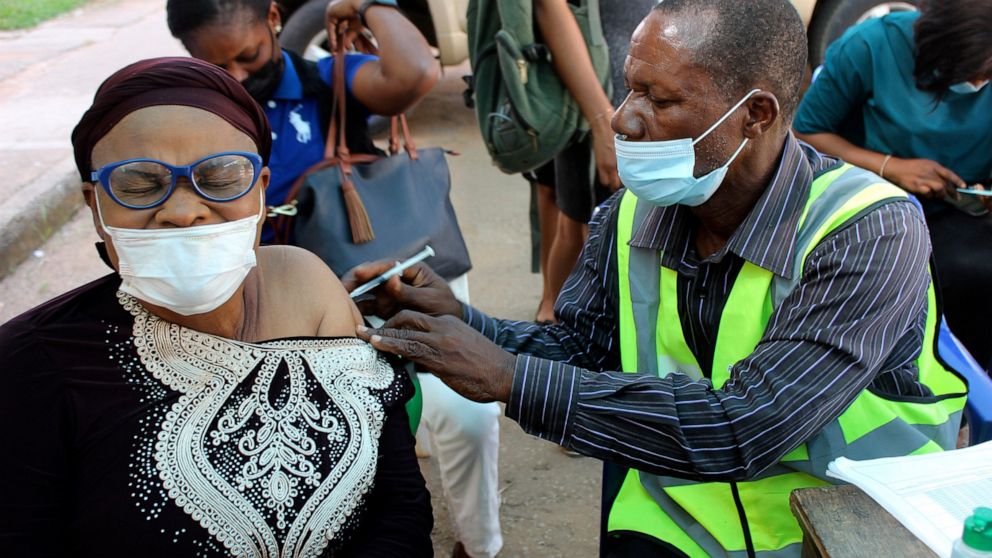 FILE - A woman receives a coronavirus vaccine in Abuja, Nigeria, Monday, Nov 29, 2021. A pandemic-weary world faces weeks of confusing uncertainty as countries restrict travel and take other steps to halt the newest potentially risky coronavirus muta