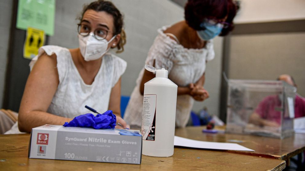 Polling station staff wear face masks to help curb the spread of the coronavirus during the Basque regional election in the village of Durango, northern Spain, Sunday, July 12, 2020. Basque authorities display special rules and practices in the prote