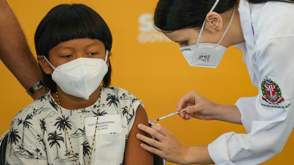 A health worker gives a shot of the Pfizer COVID-19 vaccine to 8-year-old Indigenous youth Davi Seremramiwe Xavante at the Hospital da Clinicas in Sao Paulo, Brazil, Friday, Jan. 14, 2022. The state of Sao Paulo started the COVID-19 vaccination of ch
