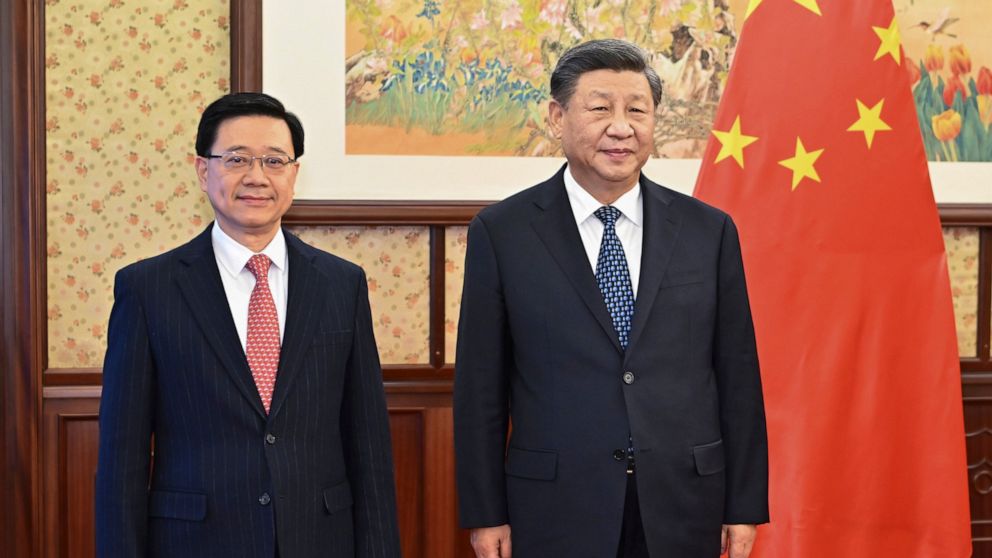 In this photo released by Xinhua News Agency, Chinese President Xi Jinping, right, stands next to Hong Kong Chief Executive John Lee before a meeting in Beijing, Friday, Dec. 23, 2022. Xi reaffirmed Beijing's commitment to follow the "one country, tw