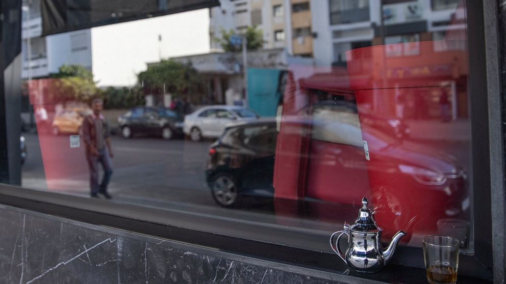 FILE - In this Monday, March 16, 2020 file photo, a glass of Moroccan tea is left by a window of a closed down coffee shop, after the Moroccan government announced further restrictions to avoid the spread of coronavirus, including closure of cafes an