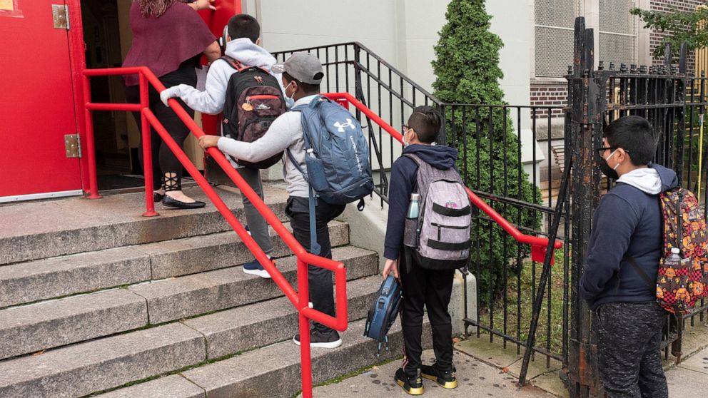 A teacher leads her students into an elementary school in the Brooklyn borough of New York on Tuesday, Sept. 29, 2020, as hundreds of thousands of elementary school students are heading back to classrooms in the city, resuming in-person learning duri