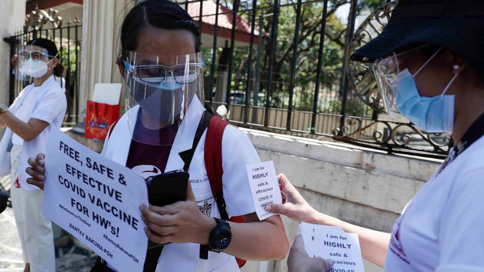 A health worker wearing a face mask and shield holds a slogan as they call on the government to give them a vaccine with the safest, highest efficacy and effectivity during a protest outside the Philippine General Hospital in Manila, Philippines on F
