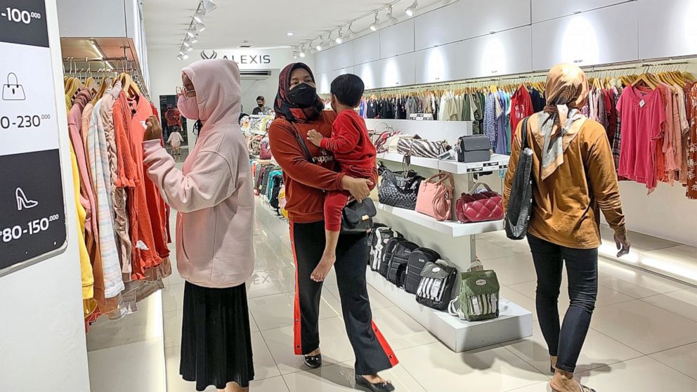 People wearing face mask browse for clothings at a shopping mall in Jakarta, Indonesia, Friday, Dec. 30. 2022. Almost three years after officials announced the first confirmed case of COVID-19 in Indonesia, the country’s leader said Friday they are l