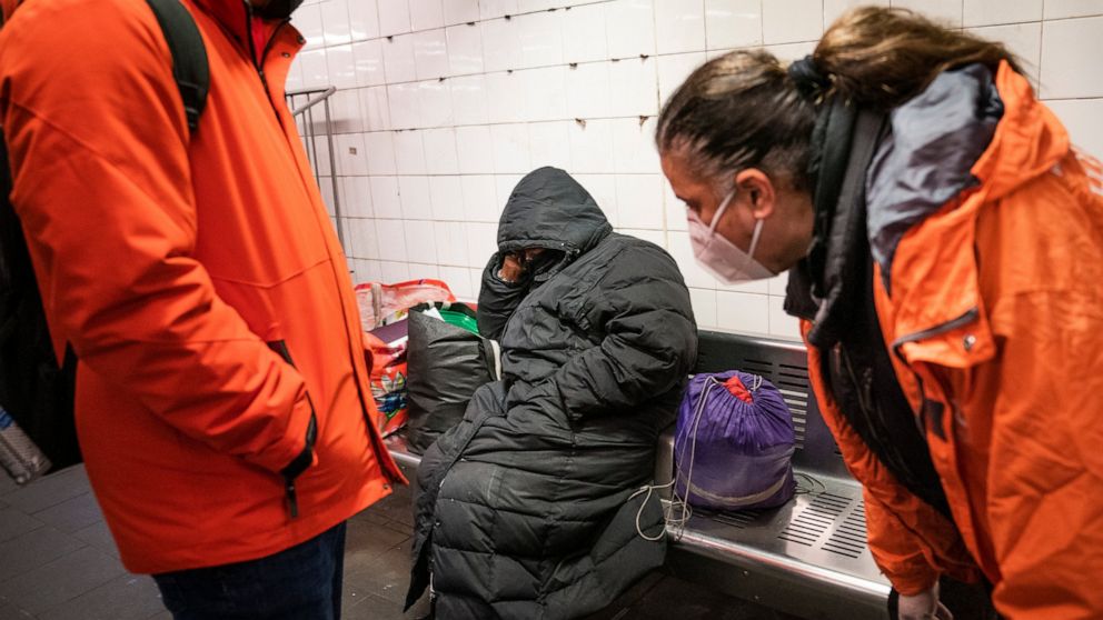 FILE - Homeless Outreach personnel reach out to a person sleeping on a bench in the Manhattan subway system, Monday, Feb. 21, 2022, in New York. In New York City's latest effort to address a mental health crisis on its streets and subways, Mayor Eric