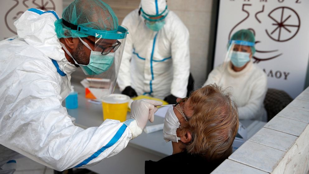 Medical staff conducts a rapid COVID test on an elderly woman in Athens, Monday, Nov. 23, 2020. Greece has seen a major resurgence of the virus after the summer, leading to dozens of deaths each day and thousands of new infections. (AP Photo/Thanassi