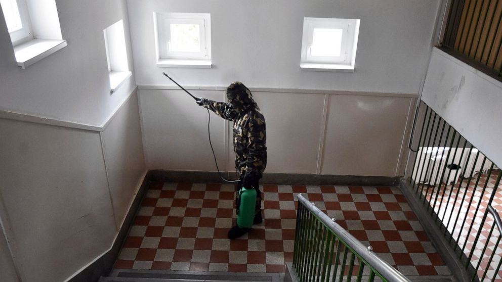 A Hungarian soldier wearing hasmat disinfects the staircase in an elementary school in Szolnok, Hungary, Monday, Oct. 26, 2020. Several pupils and teachers of the school have tested positive for the new coronavirus COVID-19 so soldiers of the Hungari