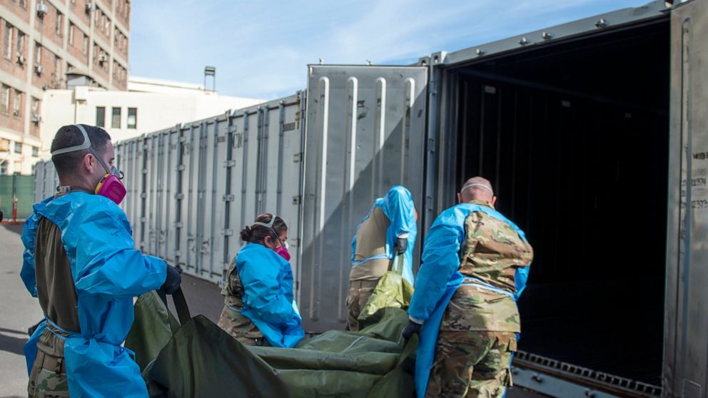 FILE - In this Jan. 12, 2021 photo provided by the Los Angeles County Department of Medical Examiner-Coroner, National Guard members assisting with processing COVID-19 deaths, placing them into temporary storage at the medical examiner-coroner's offi