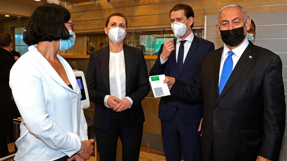 FILE - Then Israeli Prime Minister Benjamin Netanyahu, right, holds a "Green Pass," for citizens vaccinated against COVID-19, as he visits a fitness gym with Austrian Chancellor Sebastian Kurz, second right, and Danish Prime Minister Mette Frederikse