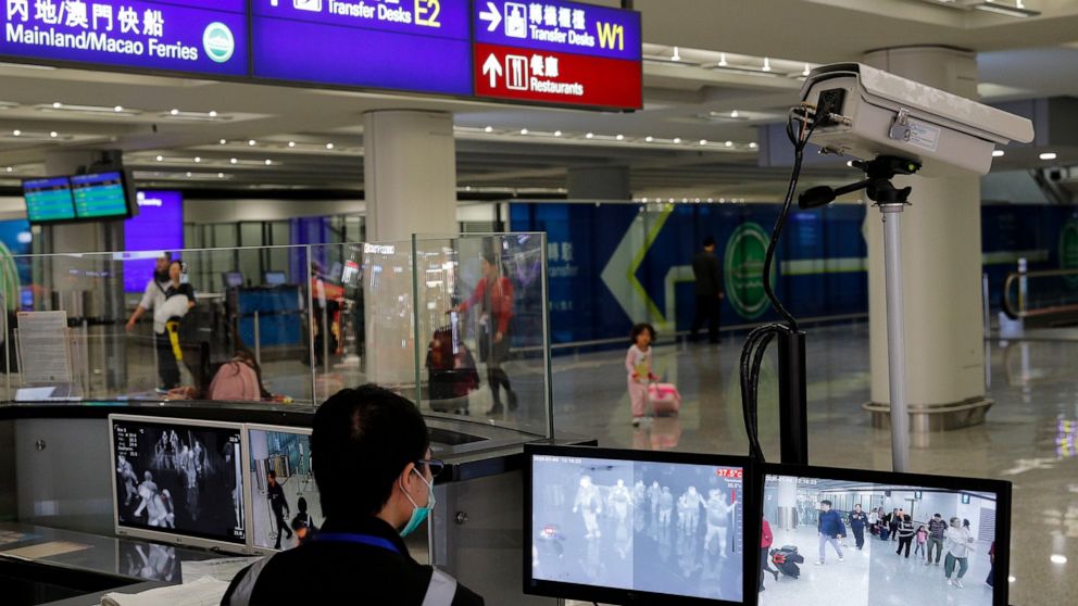 FILE - In this Jan. 4, 2020, file photo, a health surveillance officer monitors passengers arriving at the Hong Kong International airport in Hong Kong. A preliminary investigation into viral pneumonia illnesses sickening dozens of people in and arou
