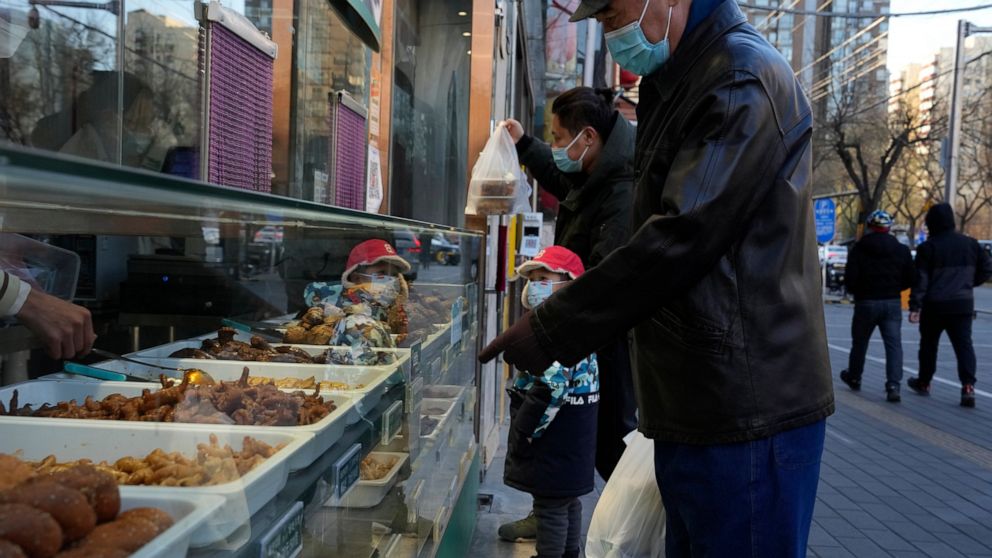 Residents go about their life with some shops re-opening for business as restrictions are eased in Beijing, Saturday, Dec. 3, 2022. Chinese authorities on Saturday announced a further easing of COVID-19 curbs with major cities such as Shenzhen and Be