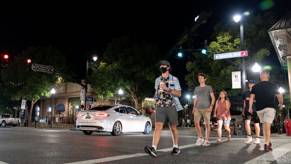 People make their way along The Strip, the University of Alabama's bar scene, Saturday, Aug. 15, 2020, in Tuscaloosa, Ala. More than 20,000 students returned to campus for the first time since spring break, with numerous school and city codes in effe