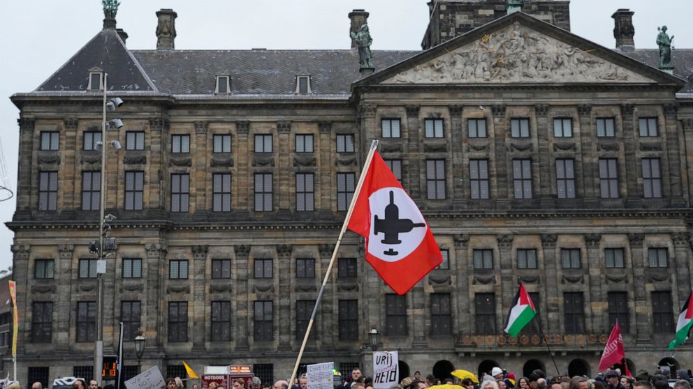 People gather on Dam Square in front of the Royal Palace to take part in a demonstration against COVID-19 restrictions in Amsterdam, Netherlands, Saturday, Nov. 20, 2021. (AP Photo/Peter Dejong)