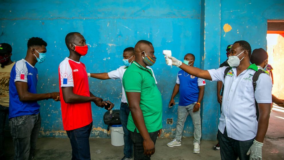 Health ministry workers check the temperature of mask-wearing fans as a precaution against the spread of the new coronavirus, before entering the stadium prior to the start of the CONCACAF World Cup qualifying soccer match between Haiti and Belize in