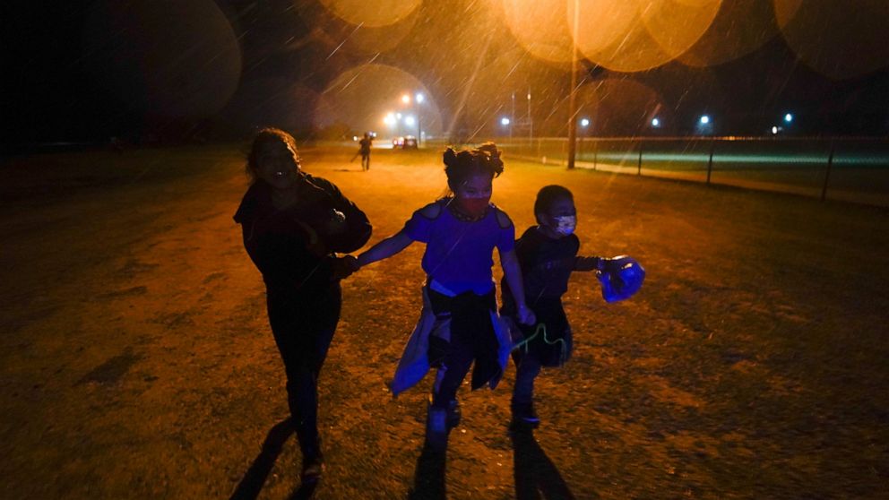 FILE - In this May 11, 2021, file photo, three young migrants hold hands as they run in the rain at an intake area after turning themselves in upon crossing the U.S.-Mexico border in Roma, Texas. On Monday, June 21, 2021, more than a dozen immigrant