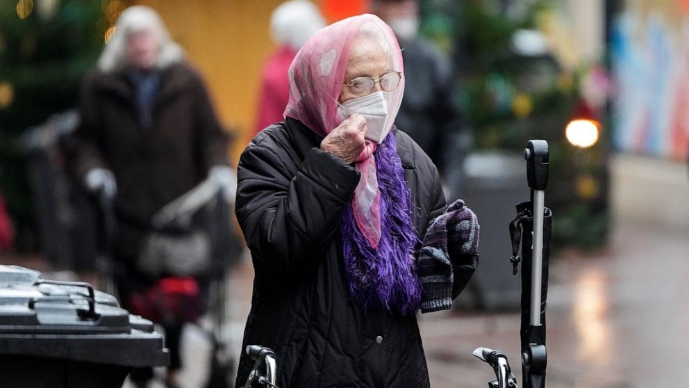 A woman prepares her face mask due to the coronavirus pandemic in Gelsenkirchen, Germany, Monday, Nov. 29, 2021. (AP Photo/Martin Meissner)