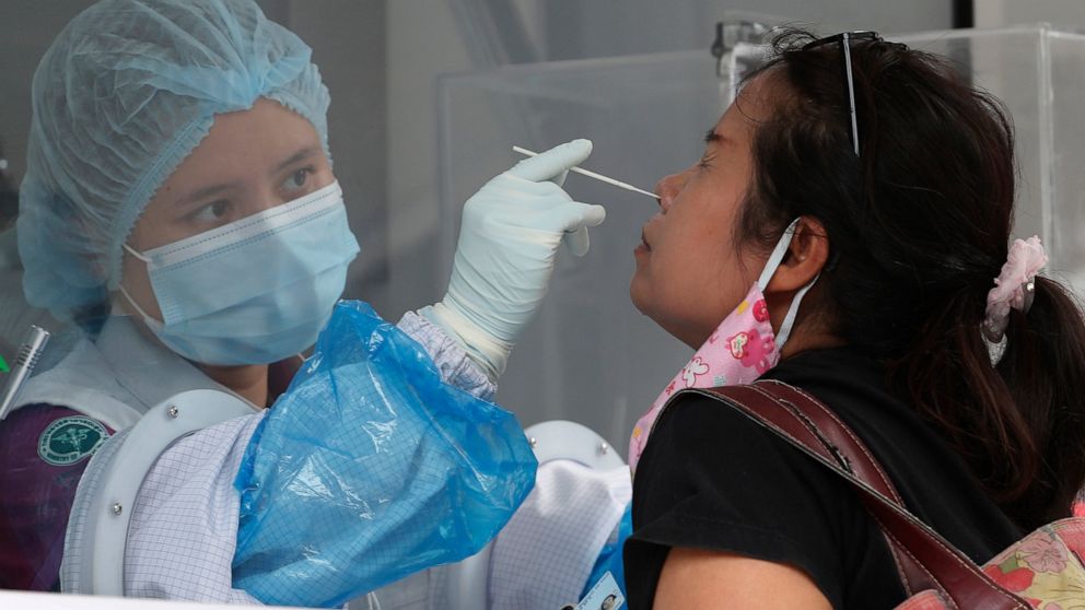 A health worker collects nasal swab sample from a worker in a local entertainment venue area where a new cluster of COVID-19 infections were found in Bangkok, Thailand, Thursday, April 8, 2021. Thailand has confirmed its first local cases of the coro