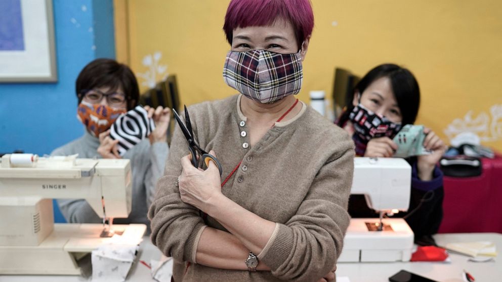 In this Monday, Feb. 17, 2020, photo, volunteers pose for a photo with their handmade cotton masks in Hong Kong. Volunteers from a Hong Kong theater group are turning their backstage skills to helping out against the new coronavirus, sewing reusable 