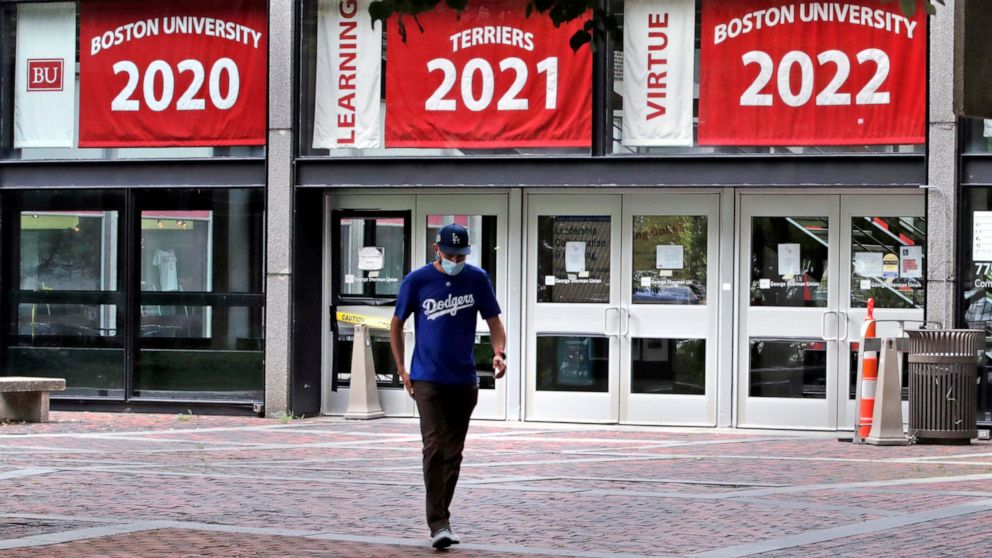 FILE - In this July 23, 2020, file photo, Weston Koenn, a graduate student from Los Angeles, leaves the Boston University student union building as he walks through the student-less campus in Boston. As more universities keep classes online this fall