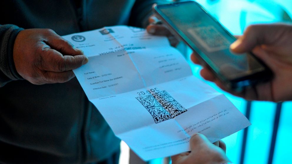 A man displays his vaccine passport before being allowed into a government office, in Tunis, Tunisia, Wednesday, Dec. 22, 2021. COVID-19 vaccination passes became obligatory for Tunisians on Wednesday. They will now be asked for proof they have recei