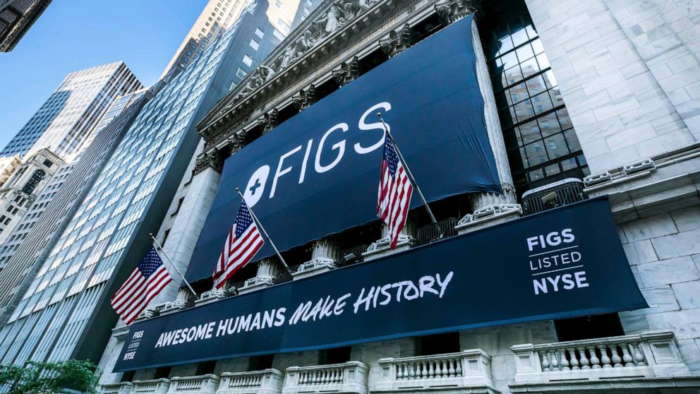 This photo provided by the New York Stock Exchange, a banner for Figs hangs on the New York Stock Exchange, Thursday, May 27, 2021. Shares of online scrubs seller Figs are soaring in their stock market debut, valuing the 8-year old company at $4.8 bi
