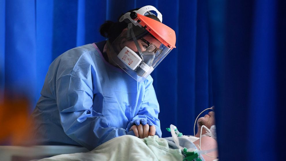 FILE - In this May 5, 2020 file photo a member of medical staff cares for a patient with coronavirus in the intensive care unit at the Royal Papworth Hospital in Cambridge, England. (Neil Hall/Pool via AP, File)