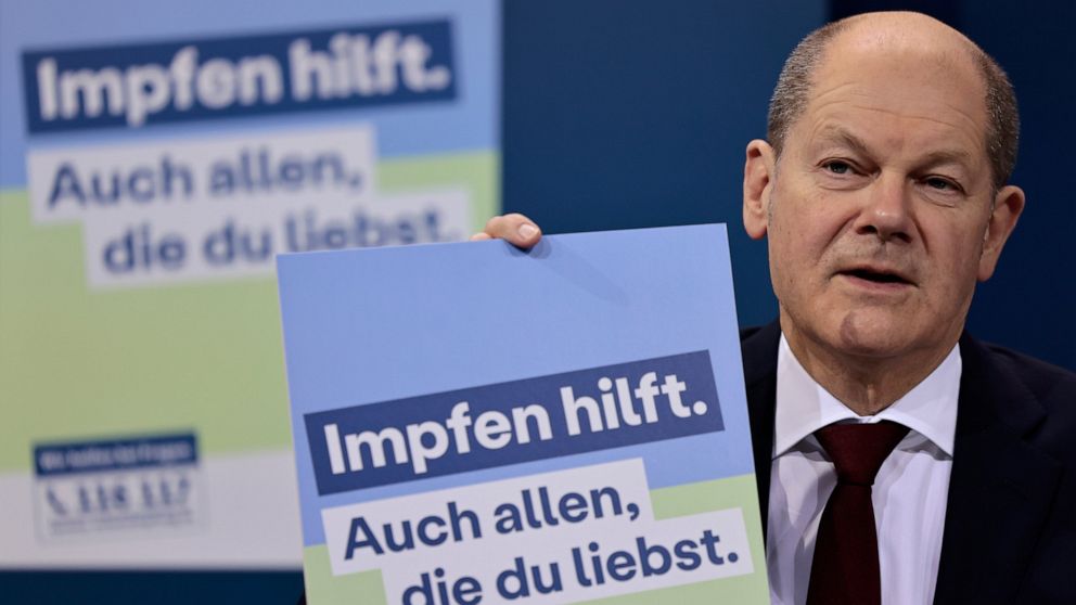 German Chancellor Olaf Scholz presents a poster of a new vaccination campaign during a press conference after a meeting at the Chancellery in Berlin, Germany, Monday, Jan. 24, 2022. German Chancellor Olaf Scholz met the governors of the country's 16 